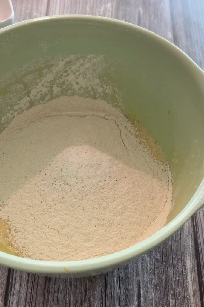 Flour, baking powder, cinnamon, nutmeg, and salt added to the wet ingredients.
