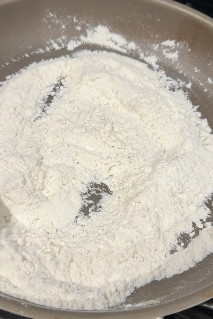 Flour toasting in a skillet for homemade Filipino polvoron.
