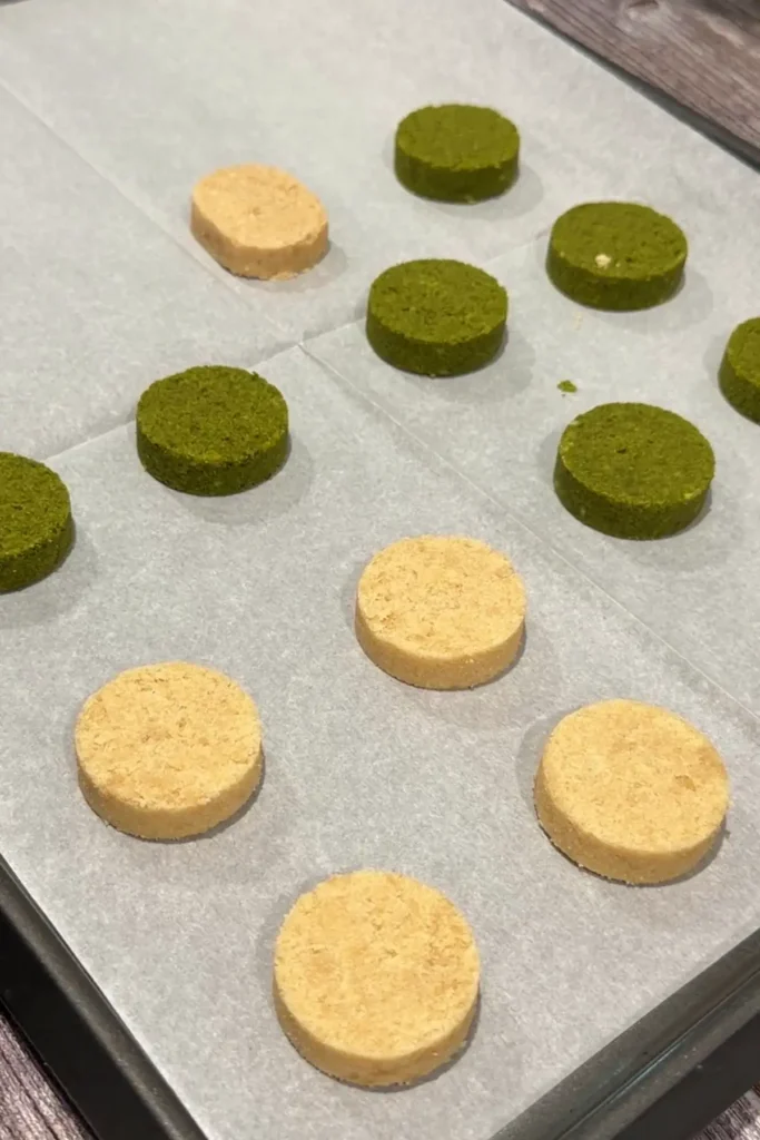 Classic and matcha polvoron arranged on a parchment-lined baking sheet.