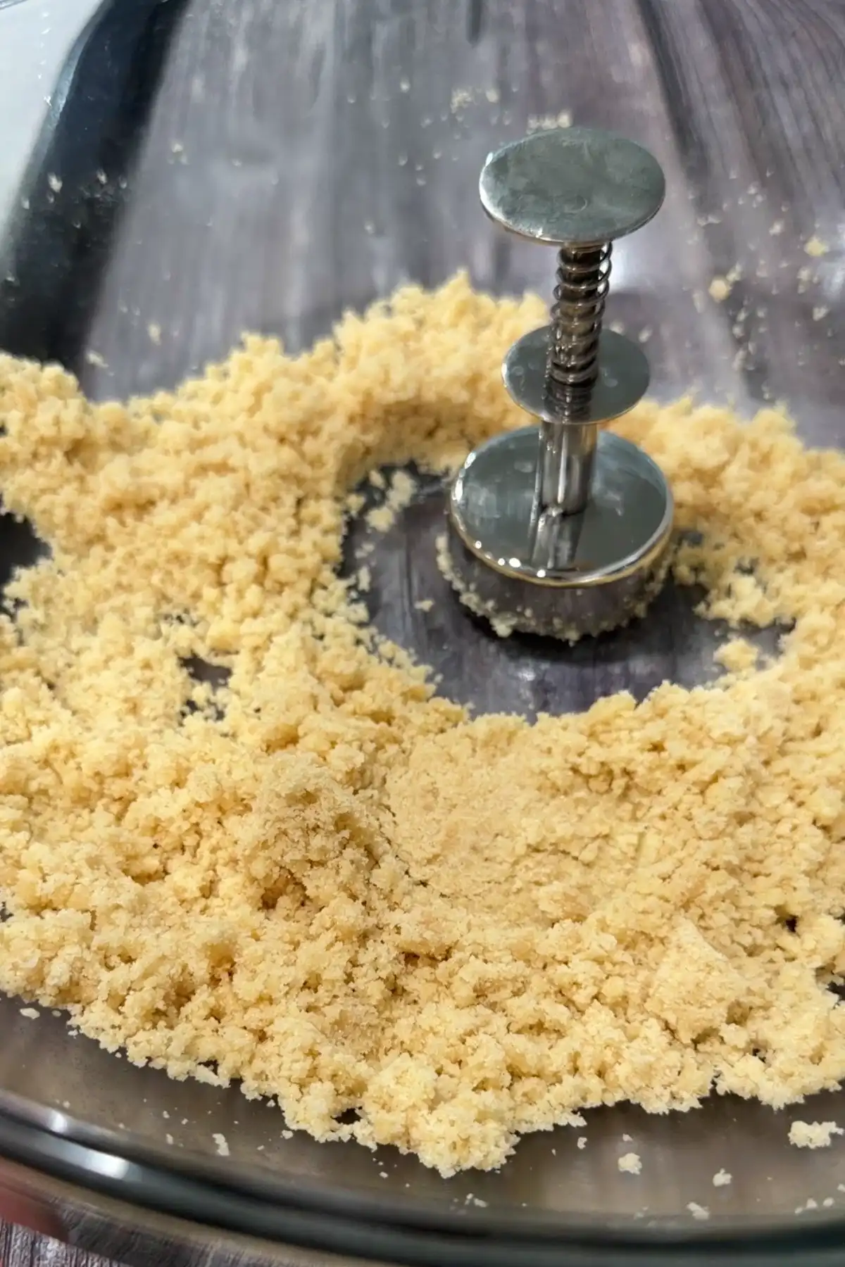 Polvoron molder pressing a crumbly toasted flour, powdered milk, sugar, and butter mixture.