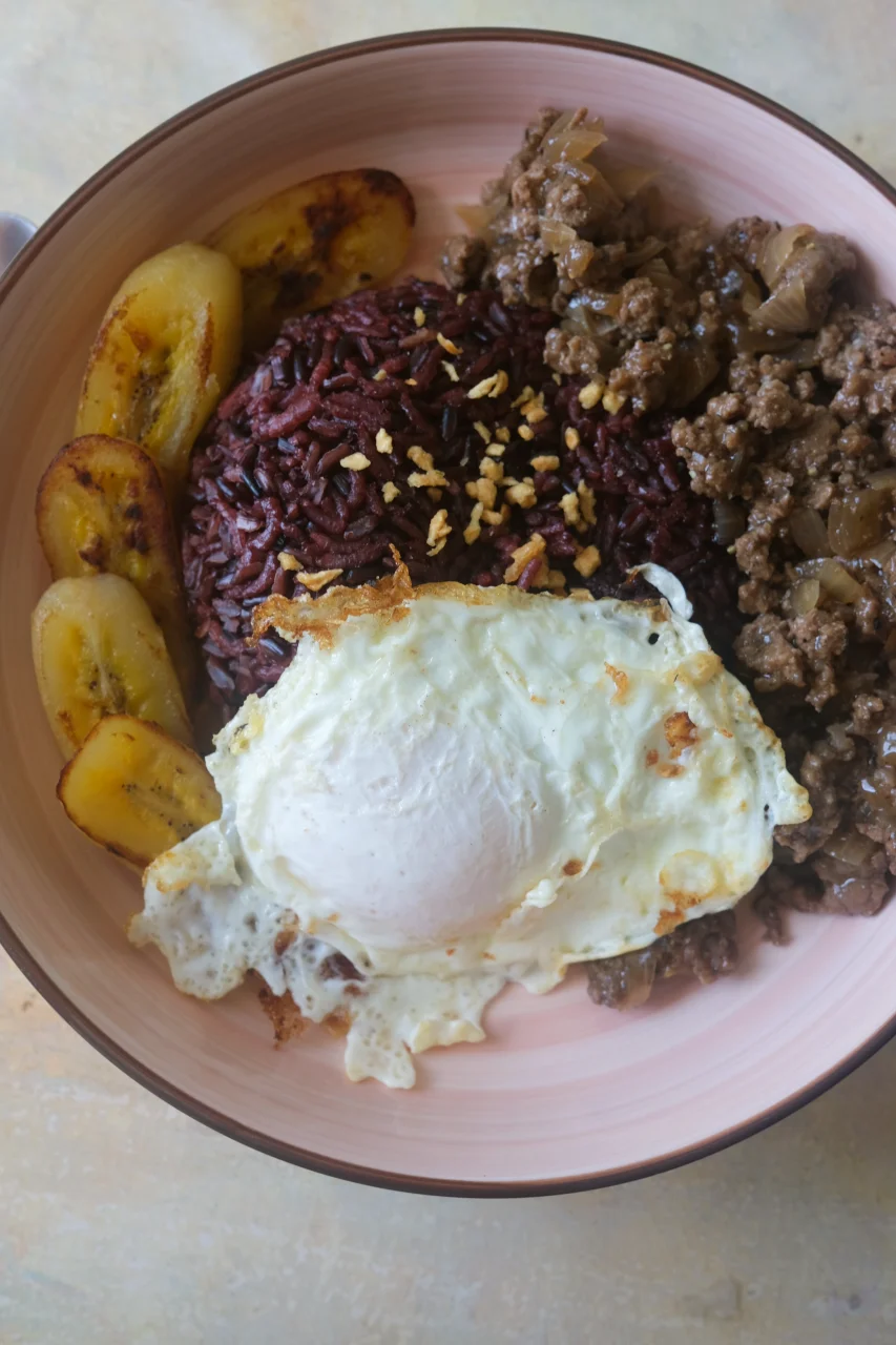 Filipino Arroz a la Cubana with ground beef, black rice, fried egg, and caramelized saba bananas.