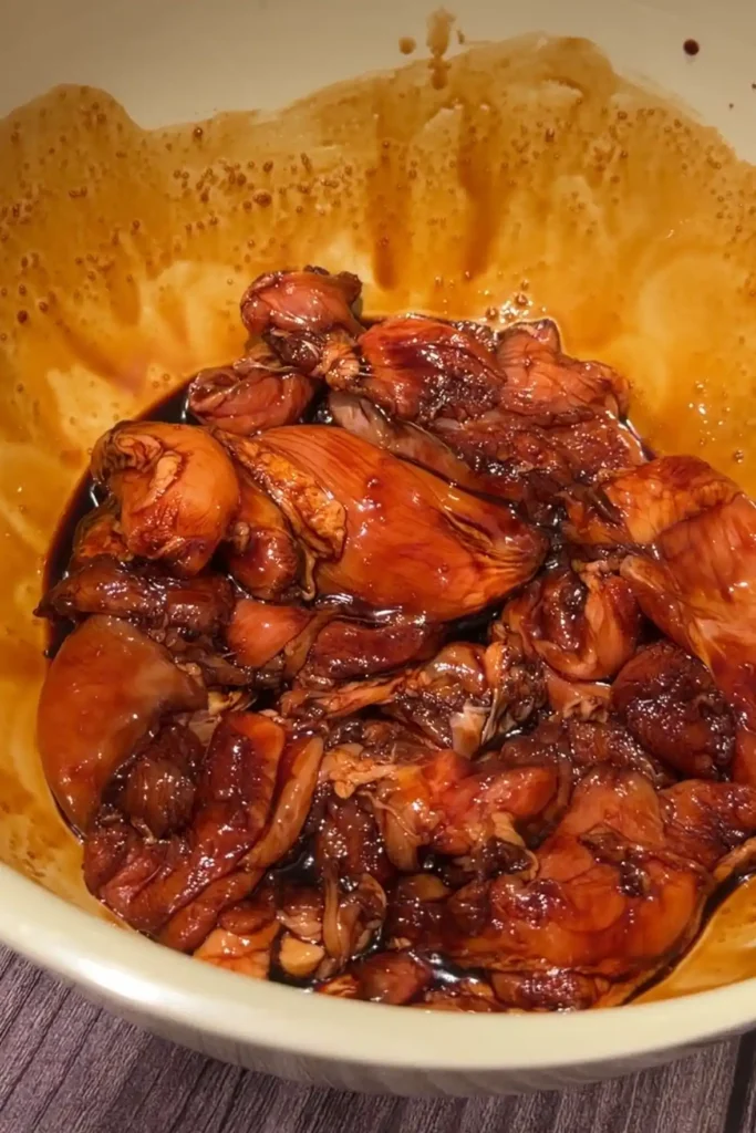 Chicken thighs marinating in soy sauce, oyster sauce, lemon juice, and seasonings.