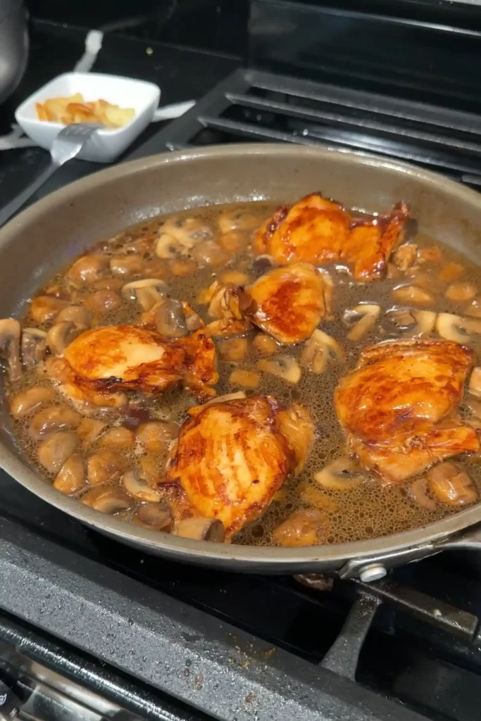 Chicken thighs and mushrooms simmering together in the gravy.