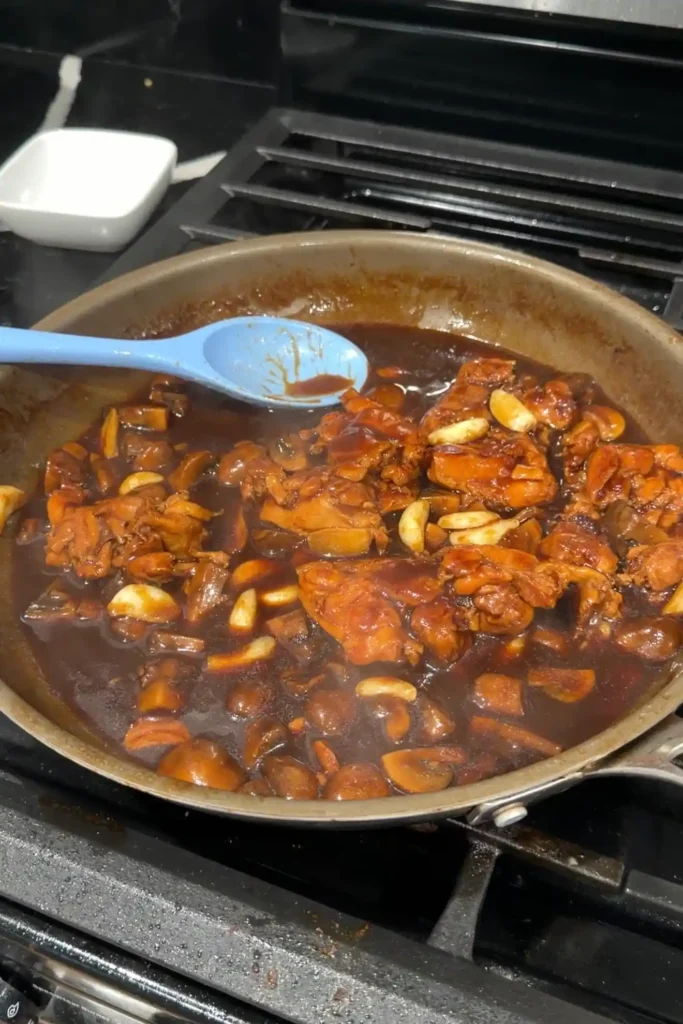 Chicken with mushrooms and golden garlic simmering in thickened brown gravy.