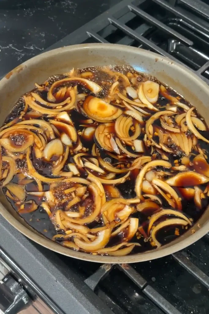 Onions and minced ginger simmering in the gyudon broth.