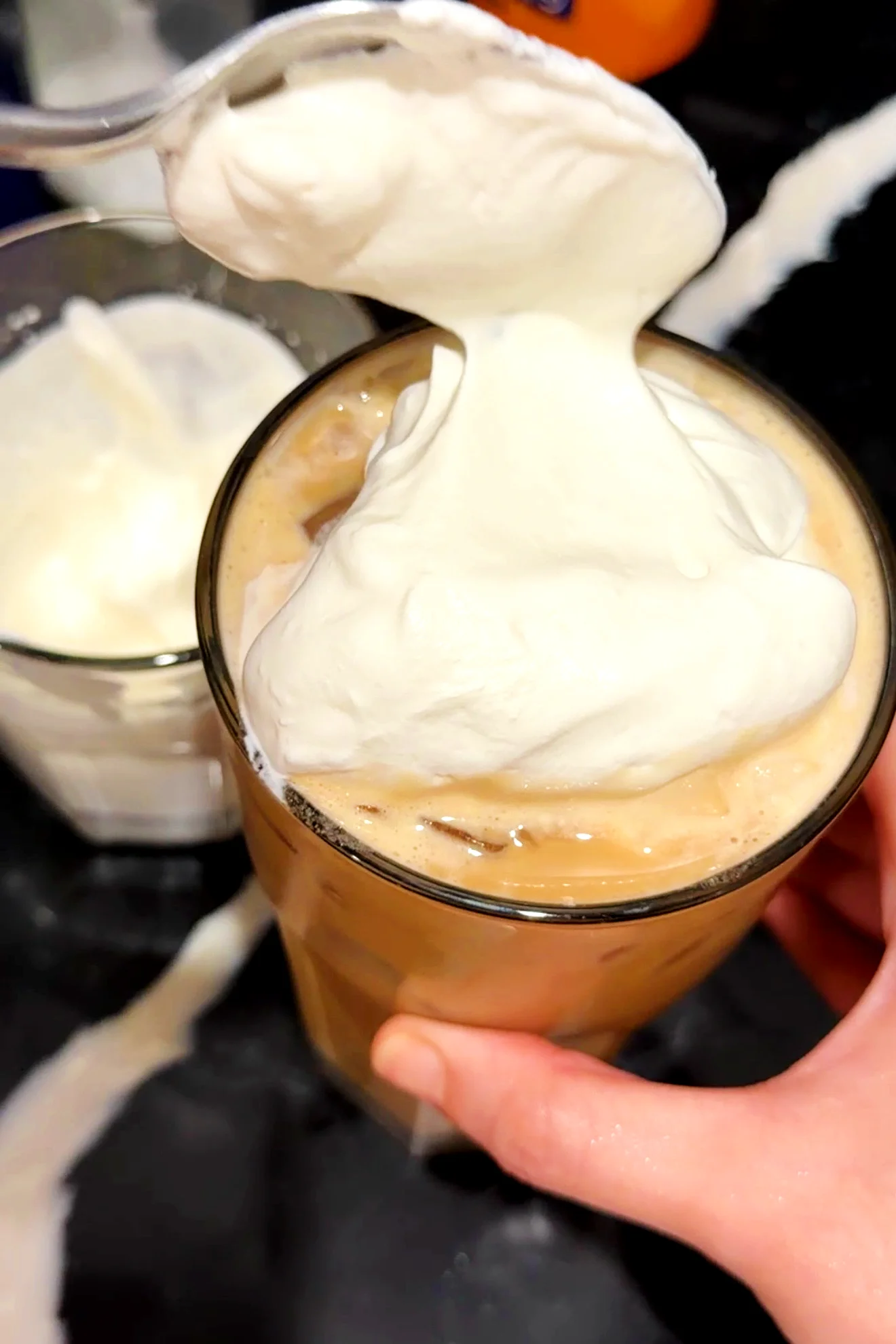 Spoonful of homemade salted caramel cream being added to an iced pumpkin spice latte.