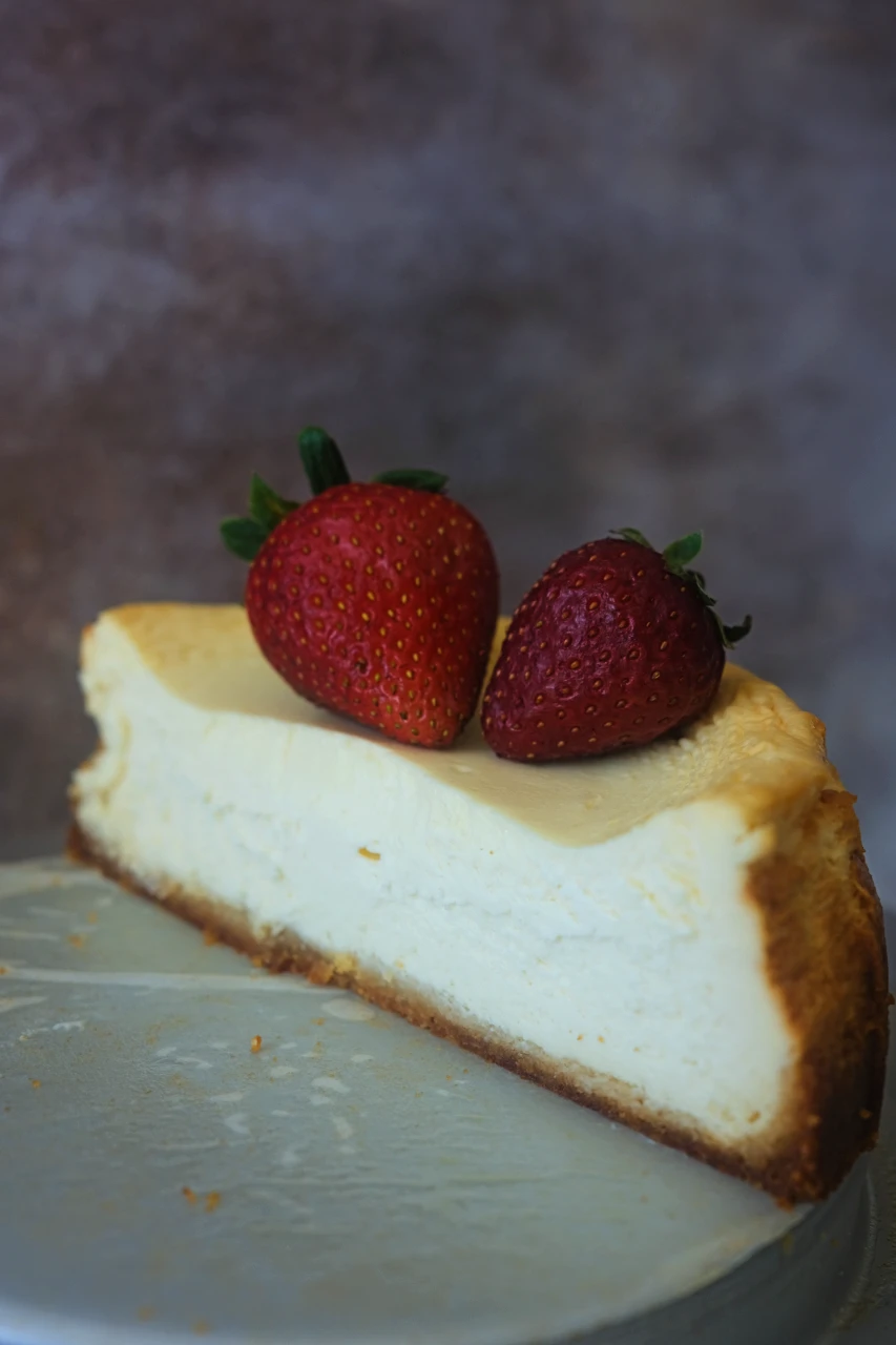 Half a keto cheesecake topped with strawberries on a cake plate