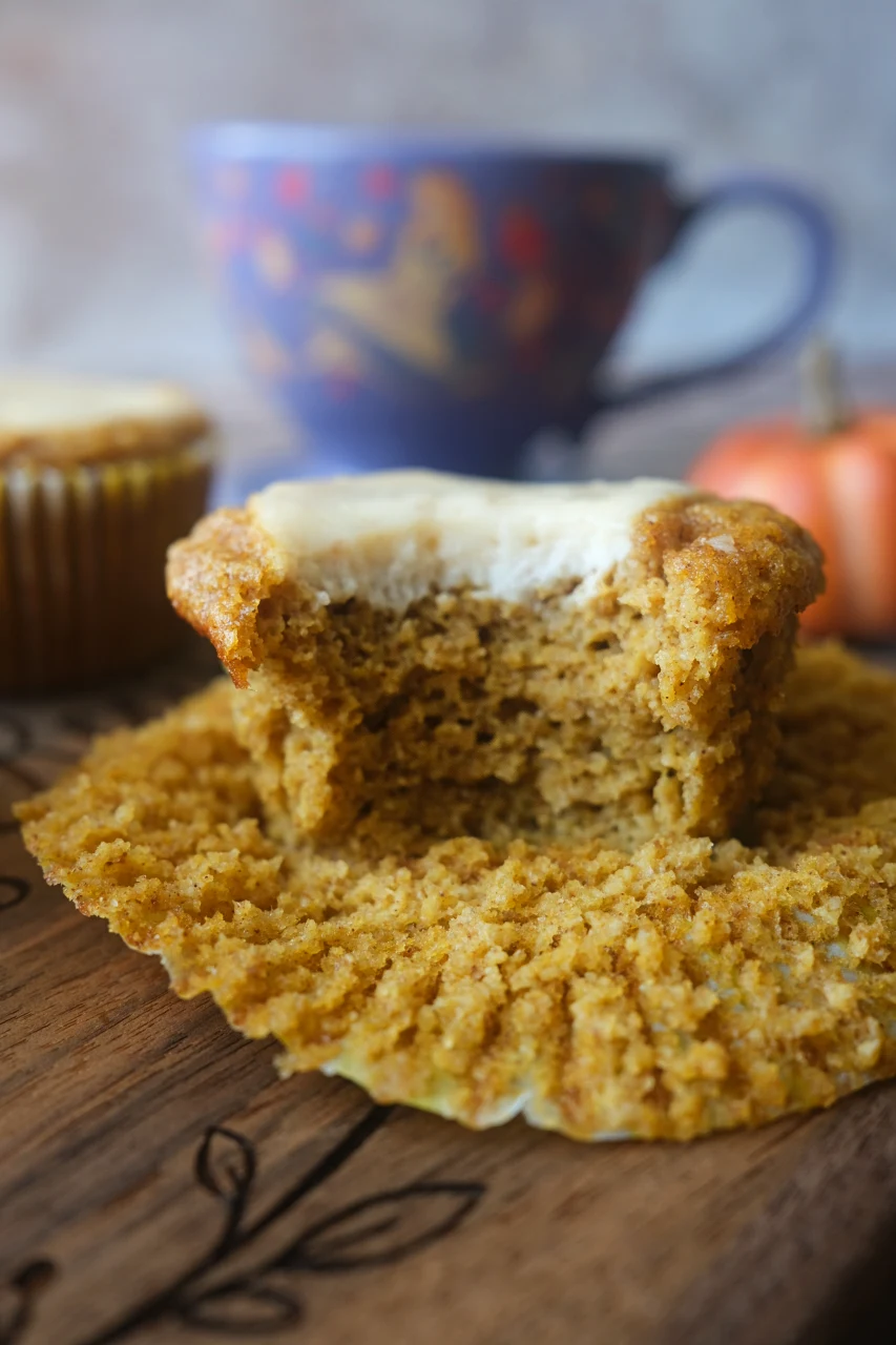 Partially eaten keto pumpkin muffin showing the golden crumb and cream cheese center.