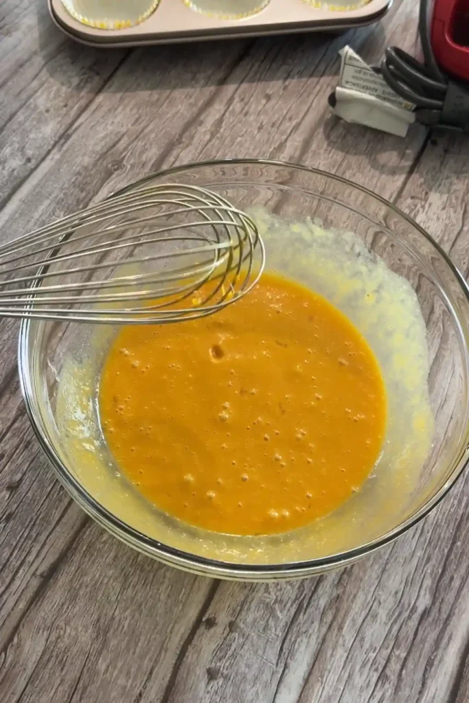 Whisked pumpkin muffin wet ingredients in a glass bowl.