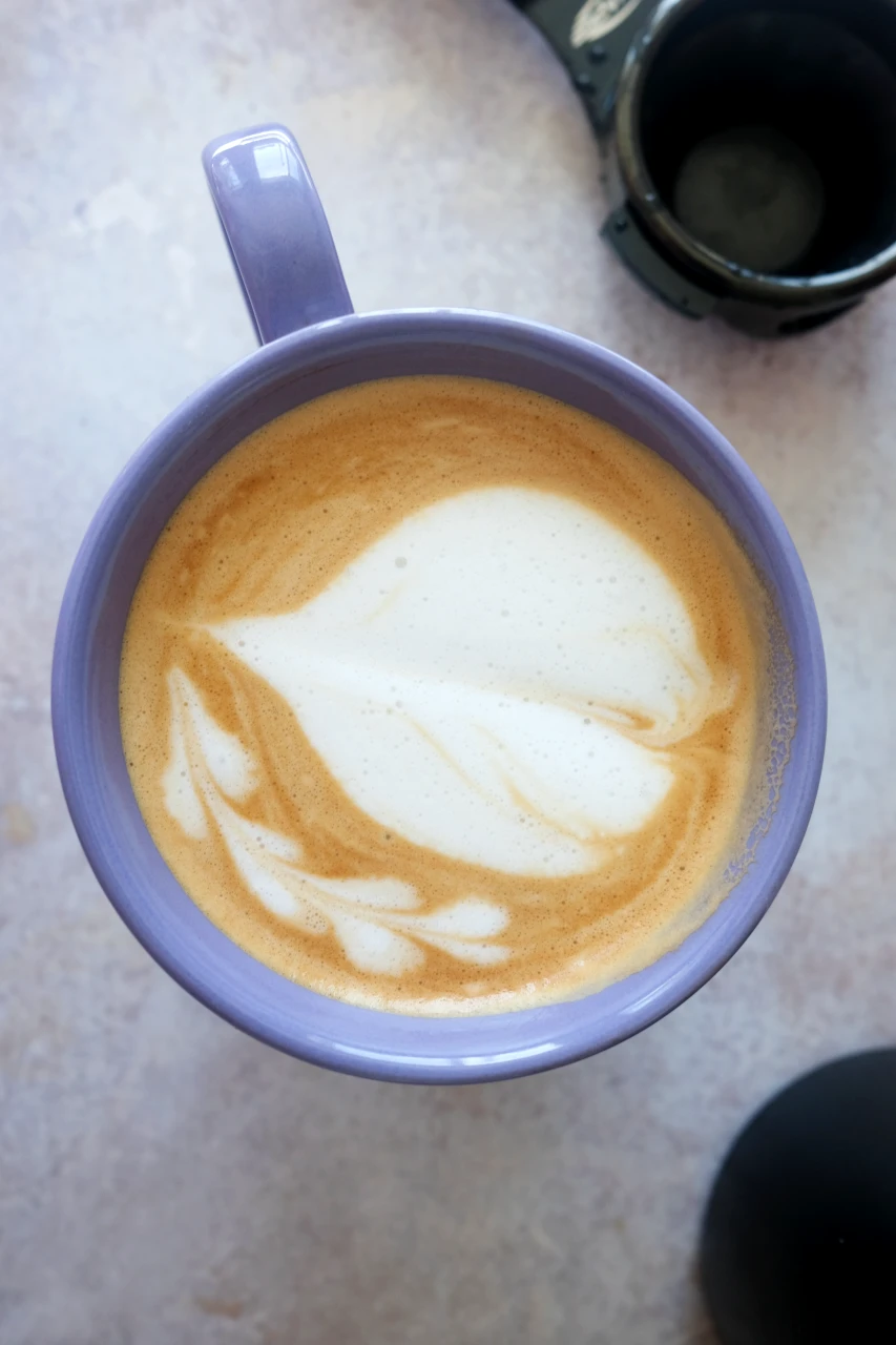 Overhead view of a salted caramel latte with creamy heart latte art in a purple mug.