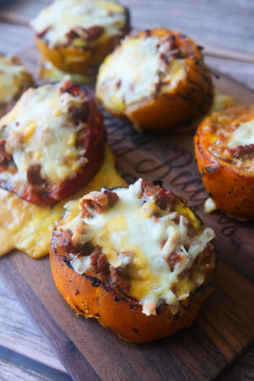 Ground turkey stuffed peppers topped with melted cheese on a wooden serving board.
