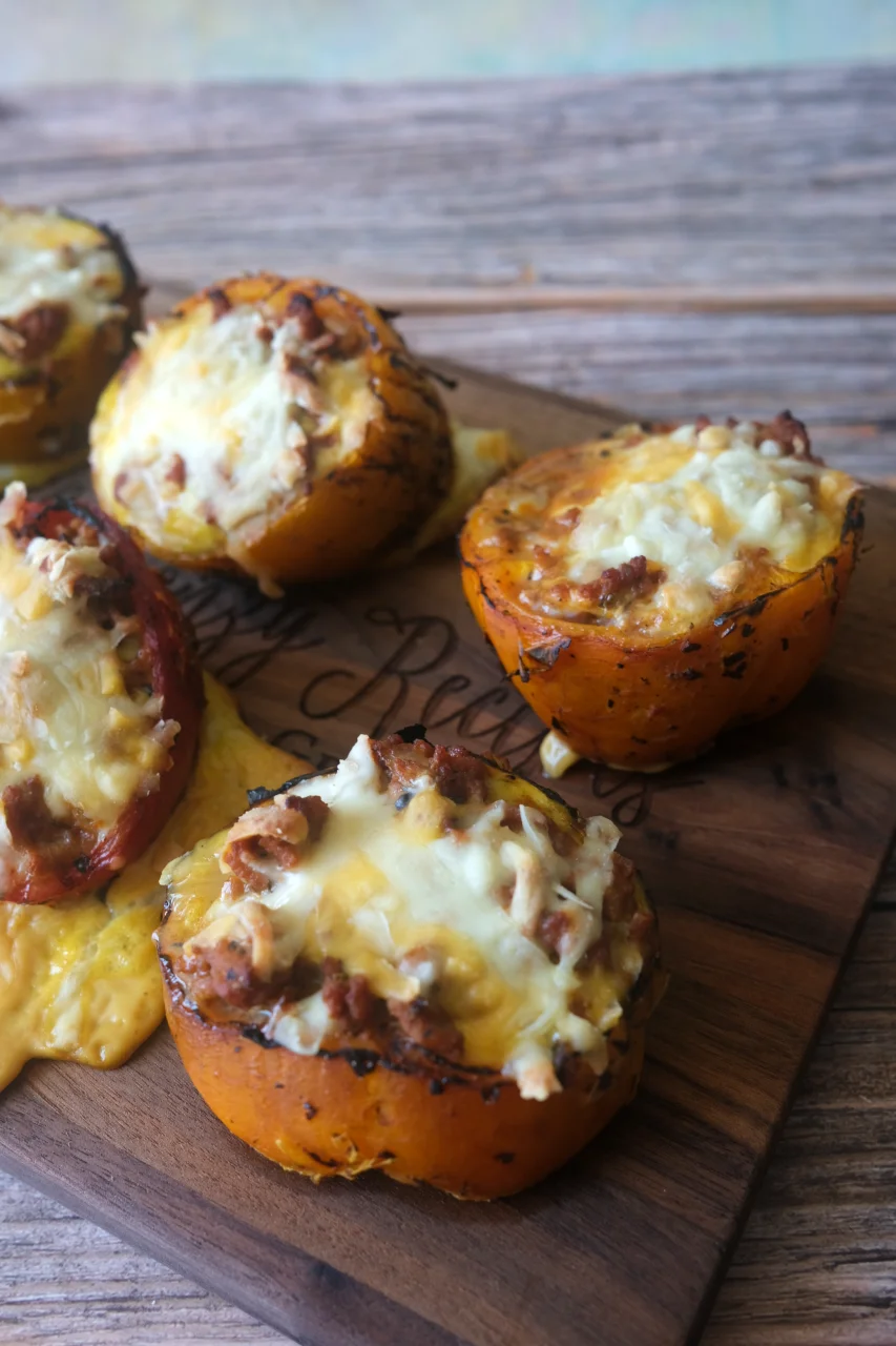 Cheesy ground turkey stuffed bell peppers with charred edges arranged on a wooden board.