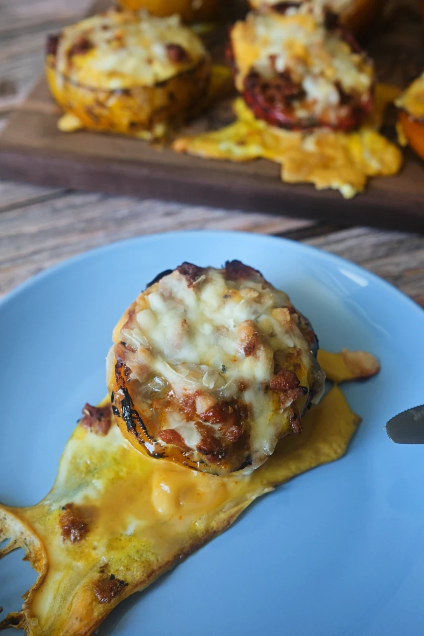 Ground turkey stuffed pepper served on a blue plate with melted cheese and roasted pepper juices.