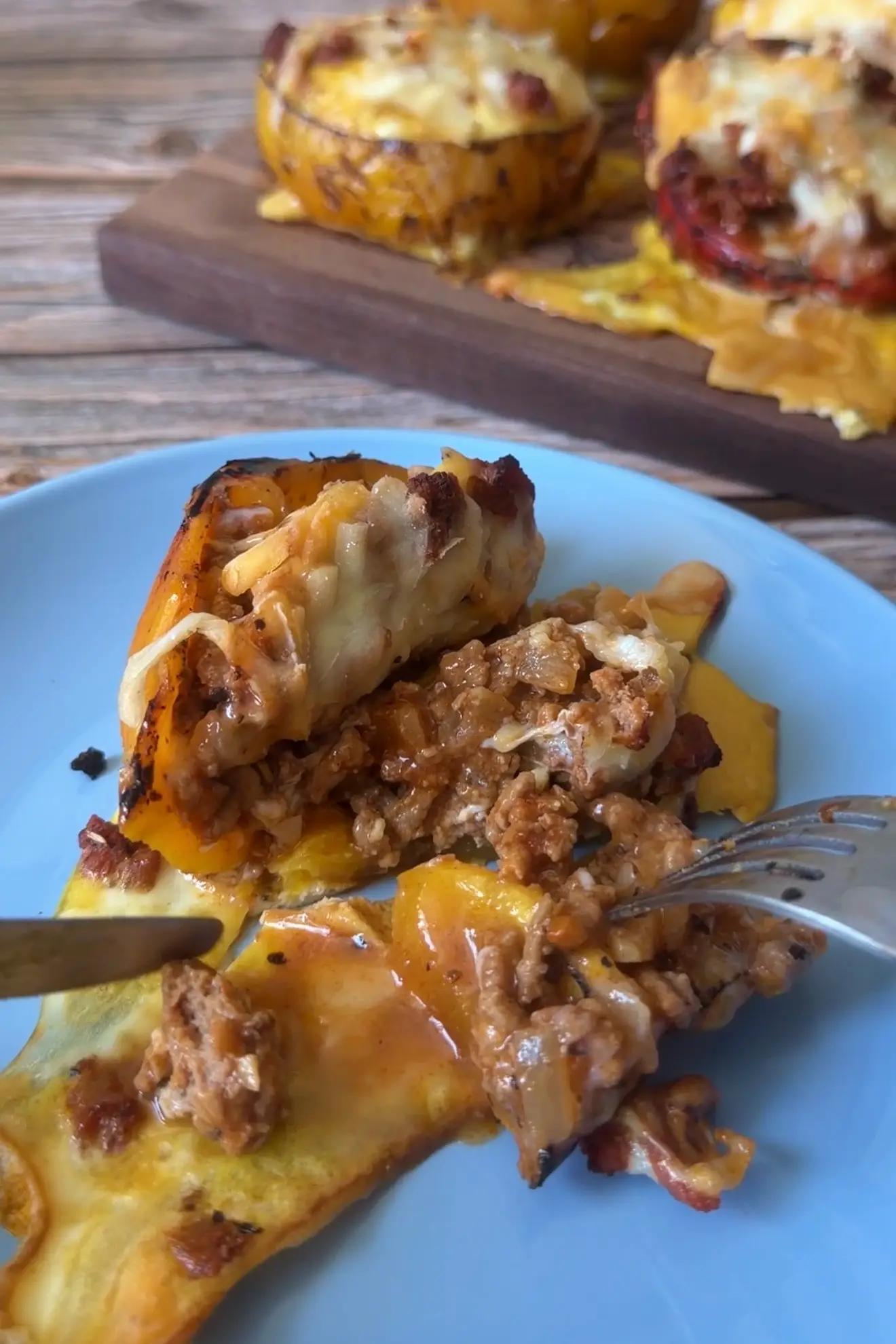 Ground turkey stuffed bell pepper cut open on a blue plate to show the cheesy turkey filling.