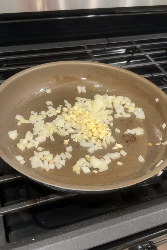 Chopped onion and garlic sautéing in a skillet for the ground turkey filling.